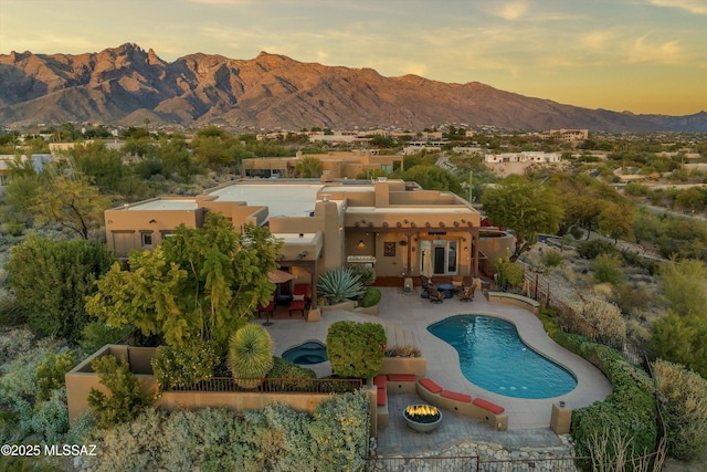 pool at dusk with a mountain view and a patio area