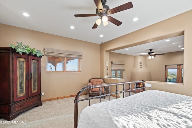 bedroom with ceiling fan, light colored carpet, and multiple windows