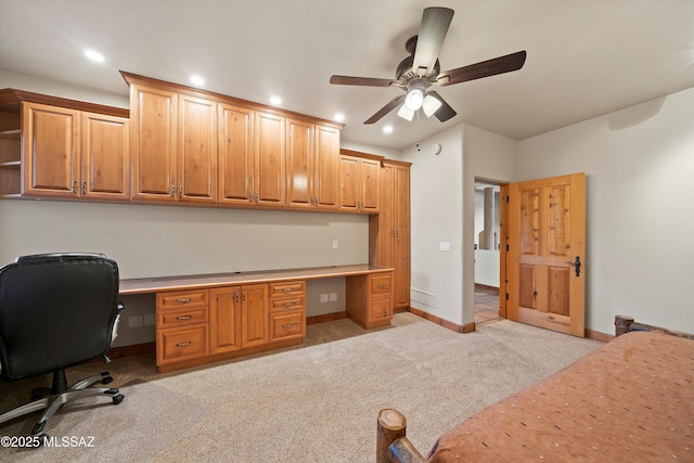 carpeted office space with ceiling fan and built in desk