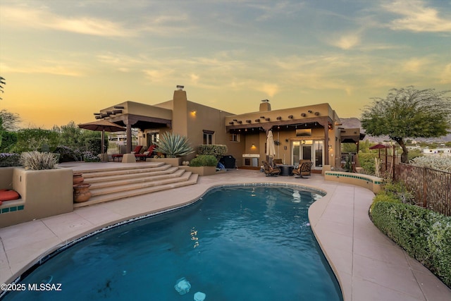 pool at dusk featuring a patio