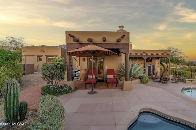 back house at dusk with a patio area and a fire pit