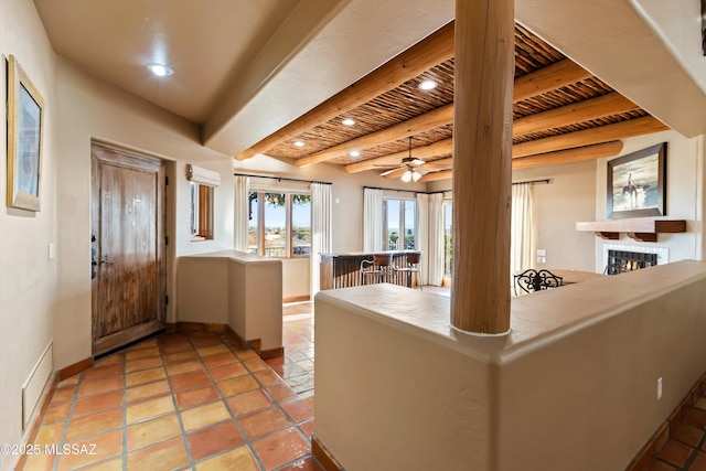 kitchen featuring ceiling fan, beamed ceiling, wooden ceiling, and light tile patterned floors