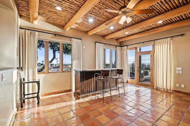 bar featuring ceiling fan, beamed ceiling, wooden ceiling, and light tile patterned floors