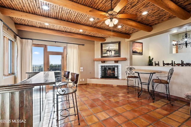 tiled dining room featuring a fireplace, beam ceiling, ceiling fan, and wooden ceiling