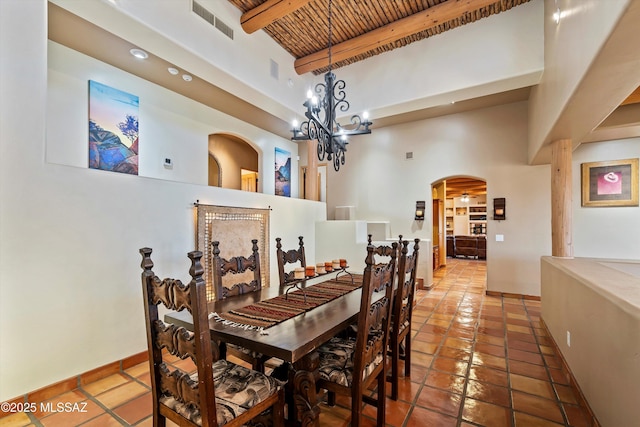 tiled dining space featuring a chandelier, beamed ceiling, wood ceiling, and a high ceiling