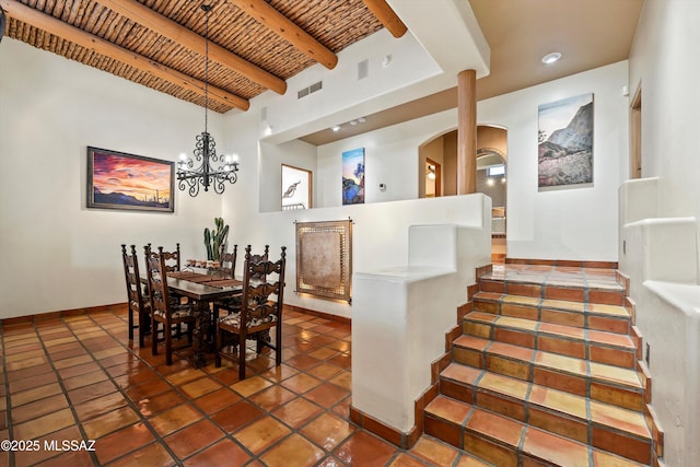 dining space featuring brick ceiling, beamed ceiling, and a chandelier