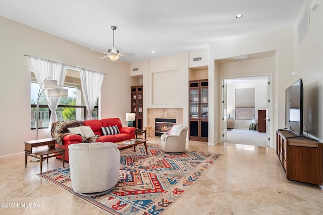 living room featuring a tile fireplace and ceiling fan