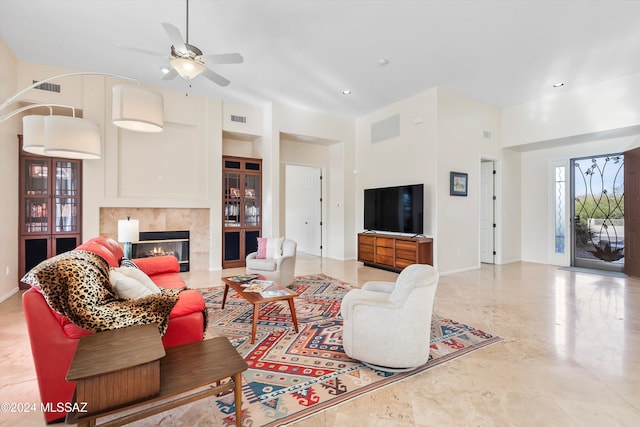 living room featuring ceiling fan, a fireplace, and a towering ceiling