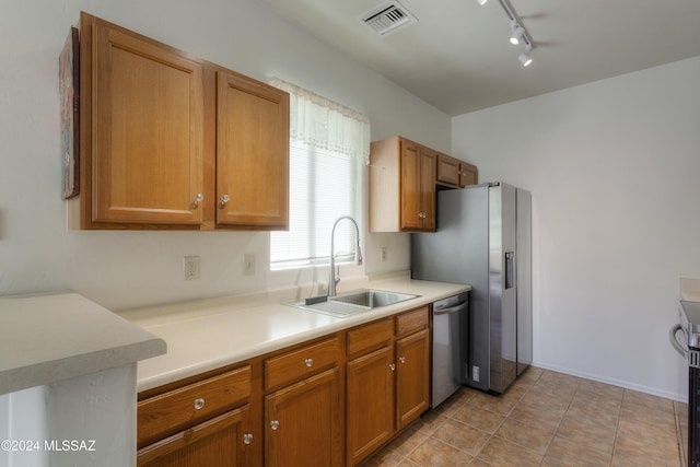 kitchen with rail lighting, sink, light tile patterned floors, and stainless steel appliances