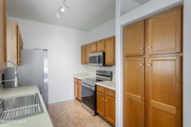 kitchen with light tile patterned floors, rail lighting, stainless steel appliances, and sink