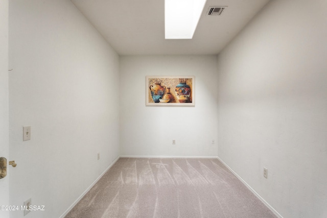 empty room with light colored carpet and a skylight