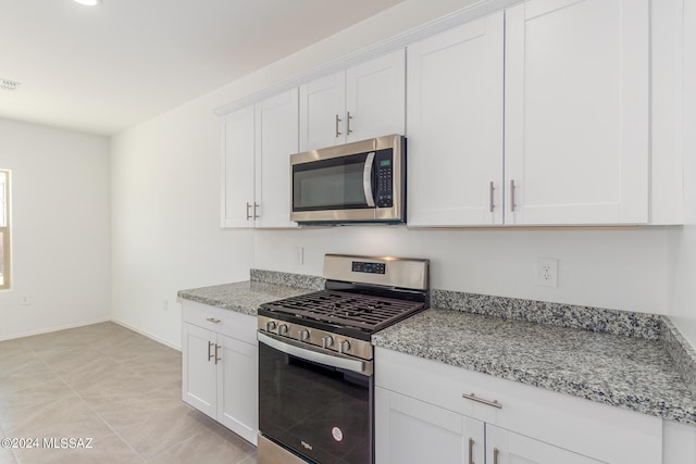 kitchen with white cabinets, light tile patterned floors, light stone countertops, and appliances with stainless steel finishes