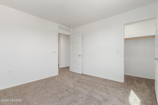 unfurnished bedroom featuring light carpet, a spacious closet, and a closet