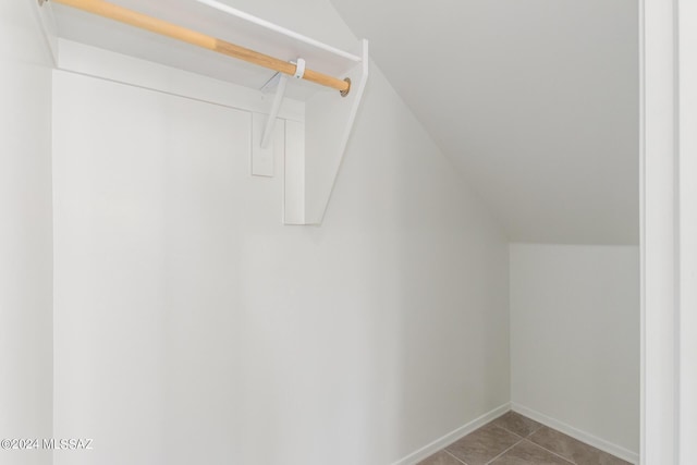 spacious closet featuring light tile patterned floors and vaulted ceiling