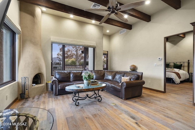 living room with beamed ceiling, a towering ceiling, light wood-type flooring, and ceiling fan