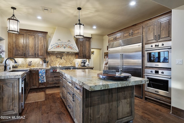 kitchen featuring pendant lighting, custom exhaust hood, a center island, dark hardwood / wood-style floors, and stainless steel appliances