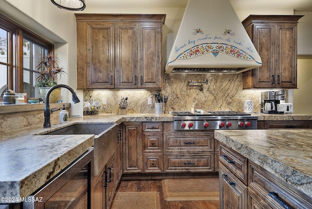 kitchen with decorative backsplash, dark hardwood / wood-style flooring, premium range hood, dark brown cabinetry, and stainless steel gas cooktop