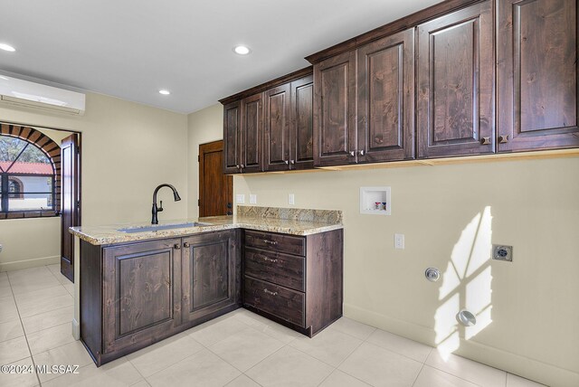 kitchen featuring a wall mounted air conditioner, kitchen peninsula, light stone countertops, sink, and light tile patterned floors