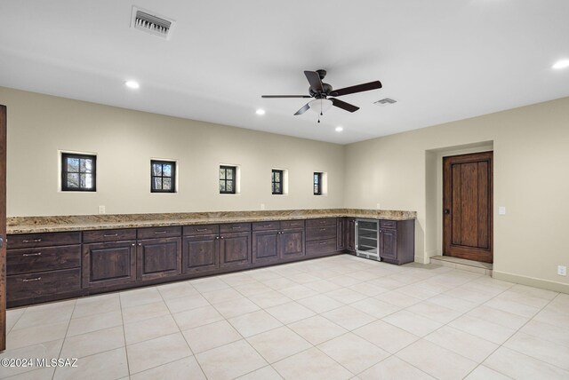 empty room with ceiling fan, light tile patterned flooring, and beverage cooler