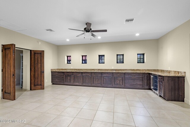 kitchen featuring kitchen peninsula, light stone counters, light tile patterned floors, and ceiling fan