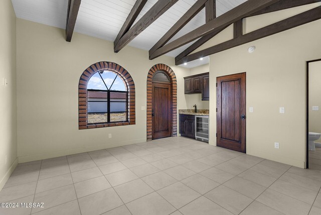 tiled spare room with indoor bar, lofted ceiling with beams, beverage cooler, and wooden ceiling