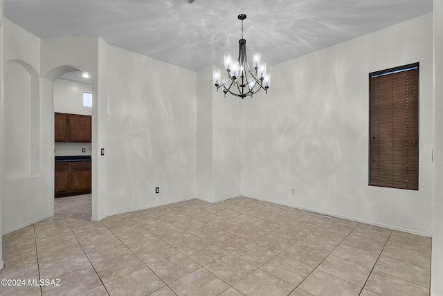 empty room featuring light tile patterned floors and an inviting chandelier