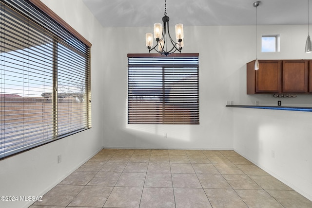 unfurnished dining area with a notable chandelier and light tile patterned floors