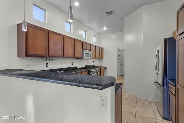 kitchen featuring kitchen peninsula, hanging light fixtures, stainless steel appliances, and a high ceiling