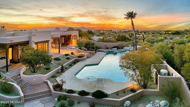 pool at dusk with a patio area