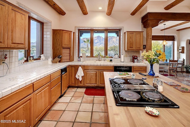 kitchen featuring cooktop, sink, tasteful backsplash, tile countertops, and black dishwasher