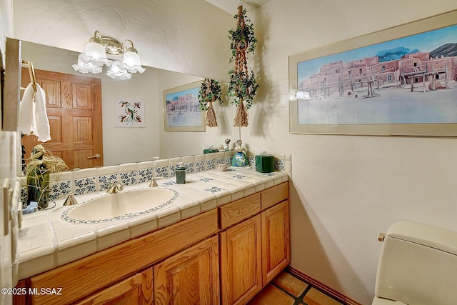 bathroom with vanity, a notable chandelier, and toilet