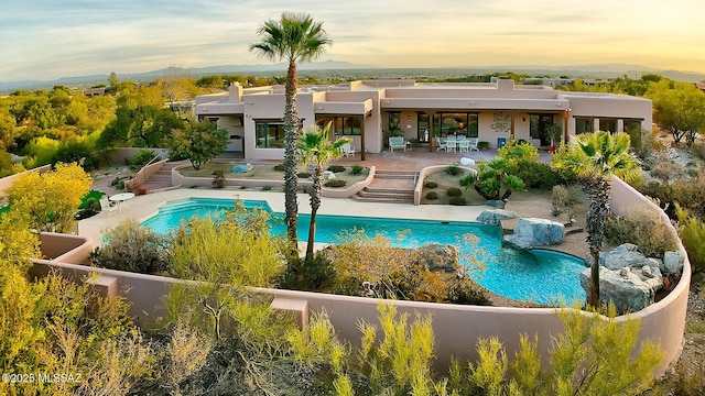 pool at dusk with a patio area