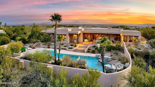 pool at dusk with a mountain view and a patio