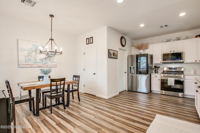 14286 E Lazy Jake Ln, Vail, AZ 85641 - kitchen featuring tasteful backsplash, light hardwood / wood-style flooring, pendant lighting, white cabinets, and appliances with stainless steel finishes