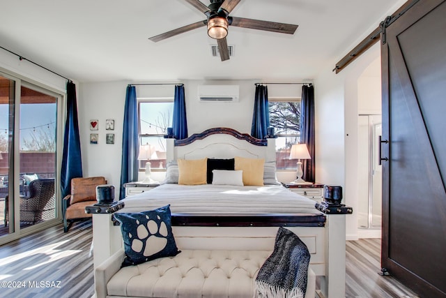 14286 E Lazy Jake Ln, Vail, AZ 85641 - bedroom with access to exterior, ceiling fan, a barn door, a wall mounted AC, and light wood-type flooring