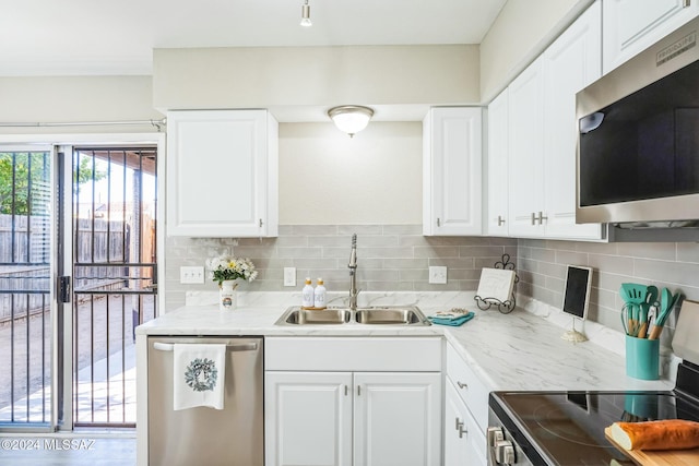 kitchen with white cabinets, sink, light stone countertops, appliances with stainless steel finishes, and tasteful backsplash