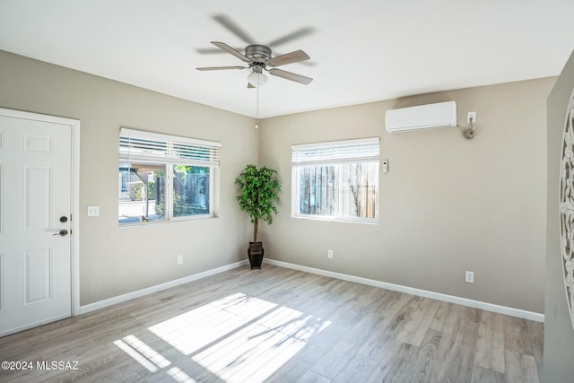 empty room with ceiling fan, a wall mounted AC, and light hardwood / wood-style flooring