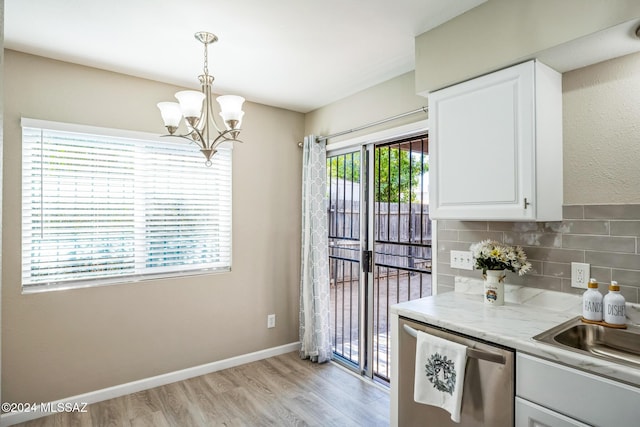 kitchen featuring dishwasher, white cabinets, decorative light fixtures, and plenty of natural light