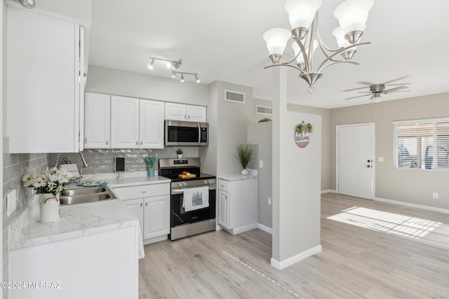 kitchen with white cabinetry, tasteful backsplash, light hardwood / wood-style flooring, pendant lighting, and appliances with stainless steel finishes