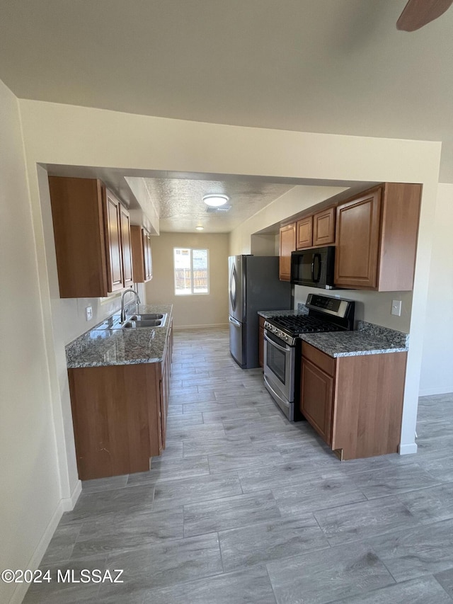 kitchen with sink, stainless steel appliances, and dark stone counters