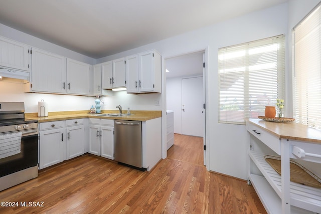 kitchen with stove, white cabinets, sink, stainless steel dishwasher, and wood-type flooring