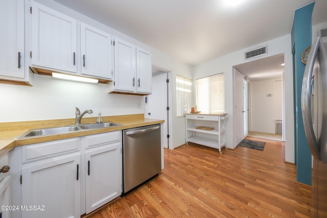 kitchen featuring white cabinetry, sink, stainless steel dishwasher, and light wood-type flooring