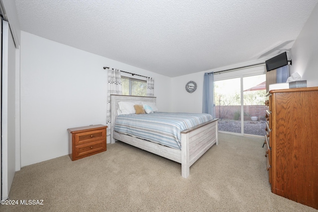 carpeted bedroom with access to outside, multiple windows, and a textured ceiling