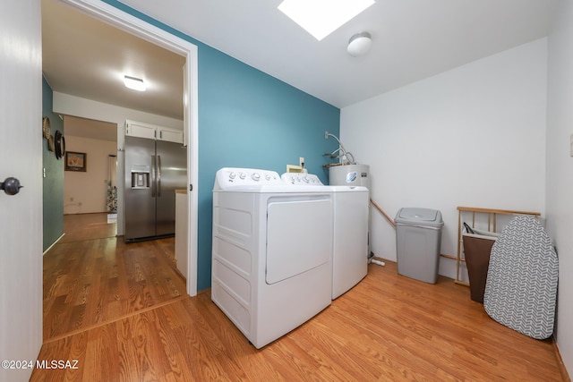 clothes washing area featuring water heater, washing machine and clothes dryer, and light hardwood / wood-style flooring