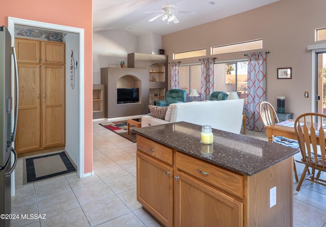 kitchen featuring light tile patterned floors, dark stone counters, ceiling fan, and a healthy amount of sunlight