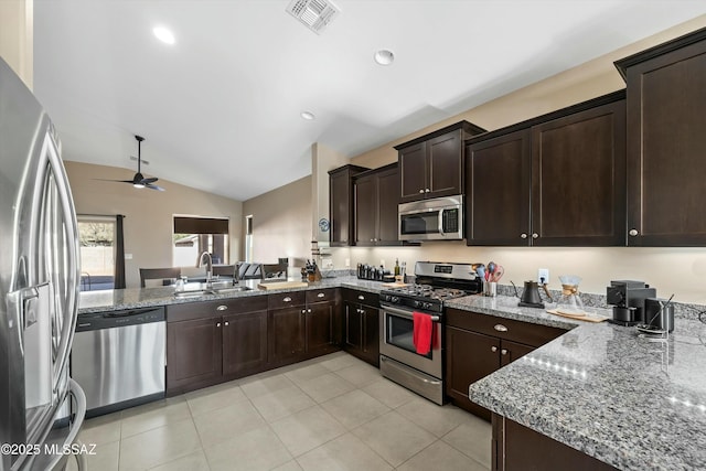 kitchen with ceiling fan, sink, stainless steel appliances, light stone counters, and vaulted ceiling