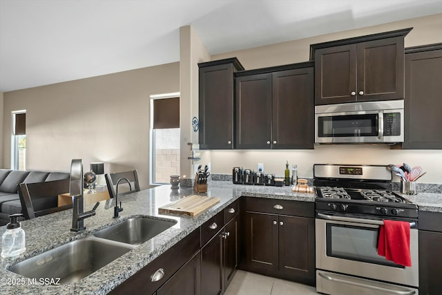 kitchen featuring sink, light tile patterned floors, dark brown cabinets, and appliances with stainless steel finishes