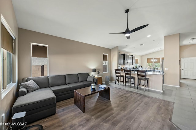 living room featuring ceiling fan, wood-type flooring, and vaulted ceiling