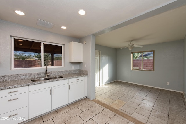 kitchen featuring light stone countertops, sink, white cabinets, and ceiling fan