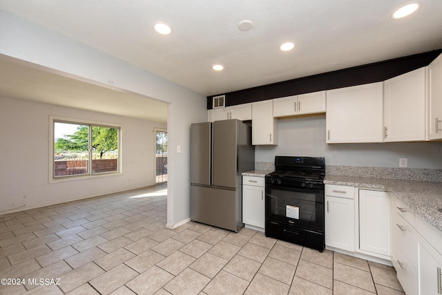 kitchen featuring black range, light stone counters, white cabinetry, and stainless steel refrigerator